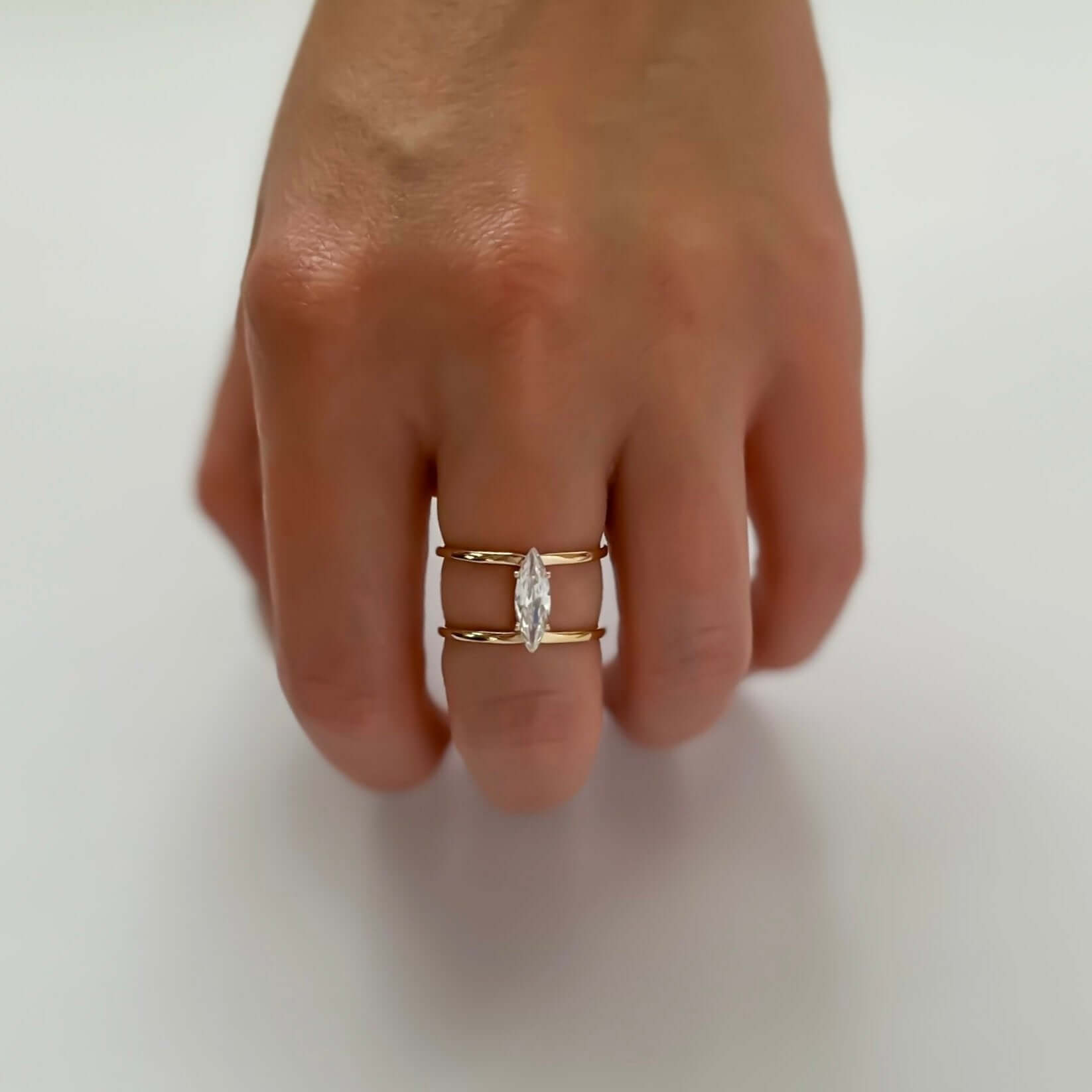 A hand showcasing the Brilliance Ring, adorned with a marquise-cut gemstone, graces the ring finger against a pristine white background.