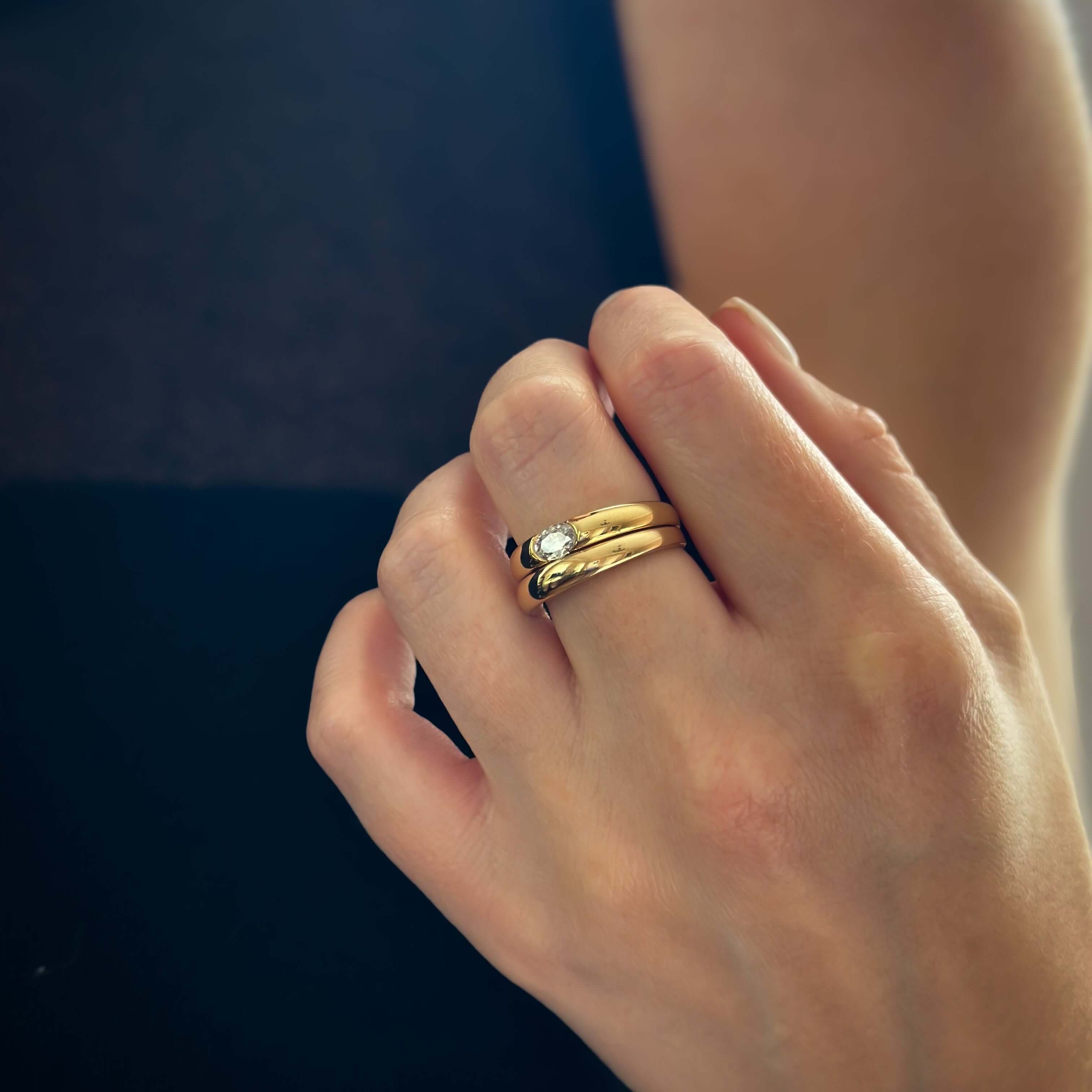Close-up of a hand wearing a Double Take Gold Ring Set with a small diamond.