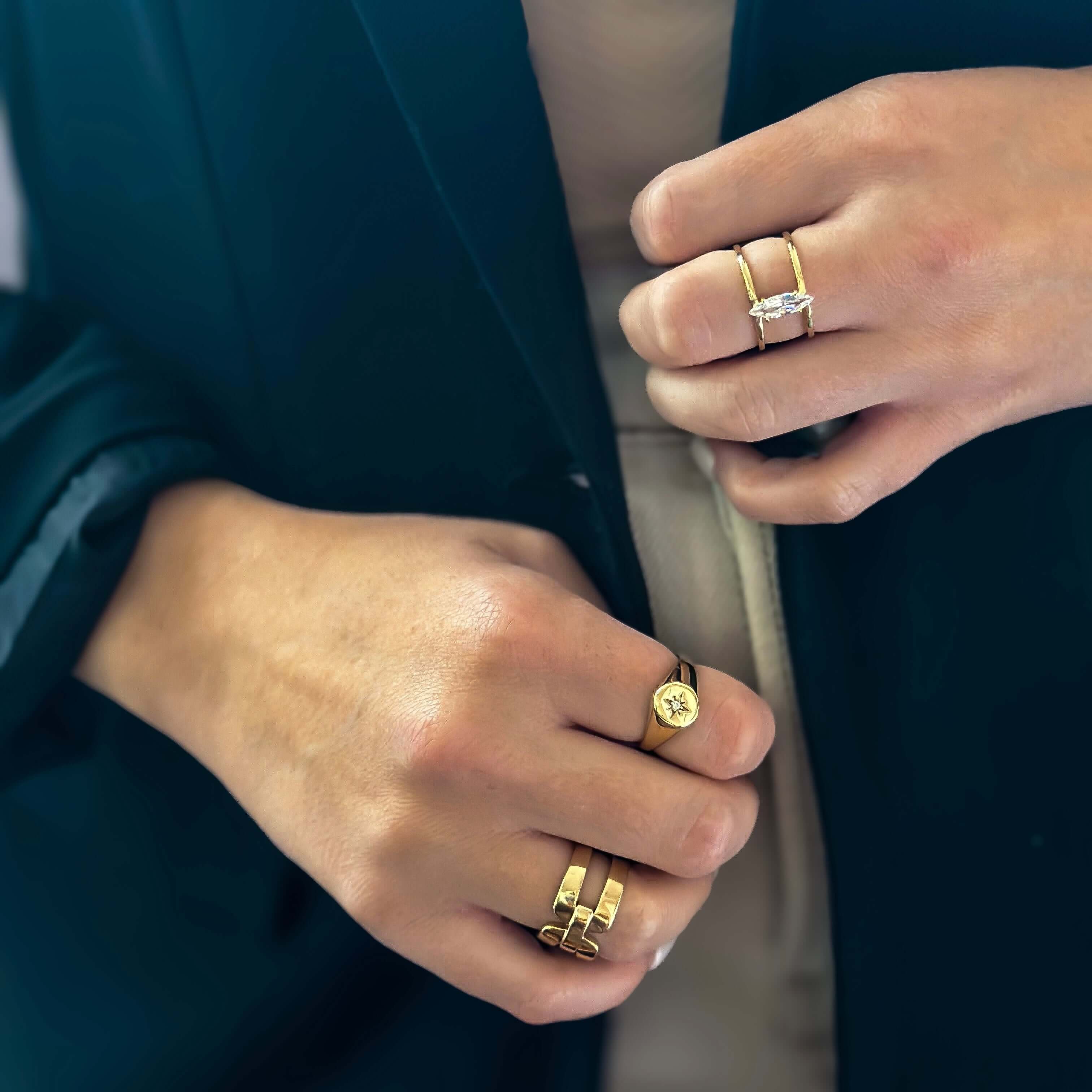 Close-up of a person wearing a dark green blazer, showcasing the quality craftsmanship of three gold rings on their fingers, including the stunning Star Gazer Signet Ring.