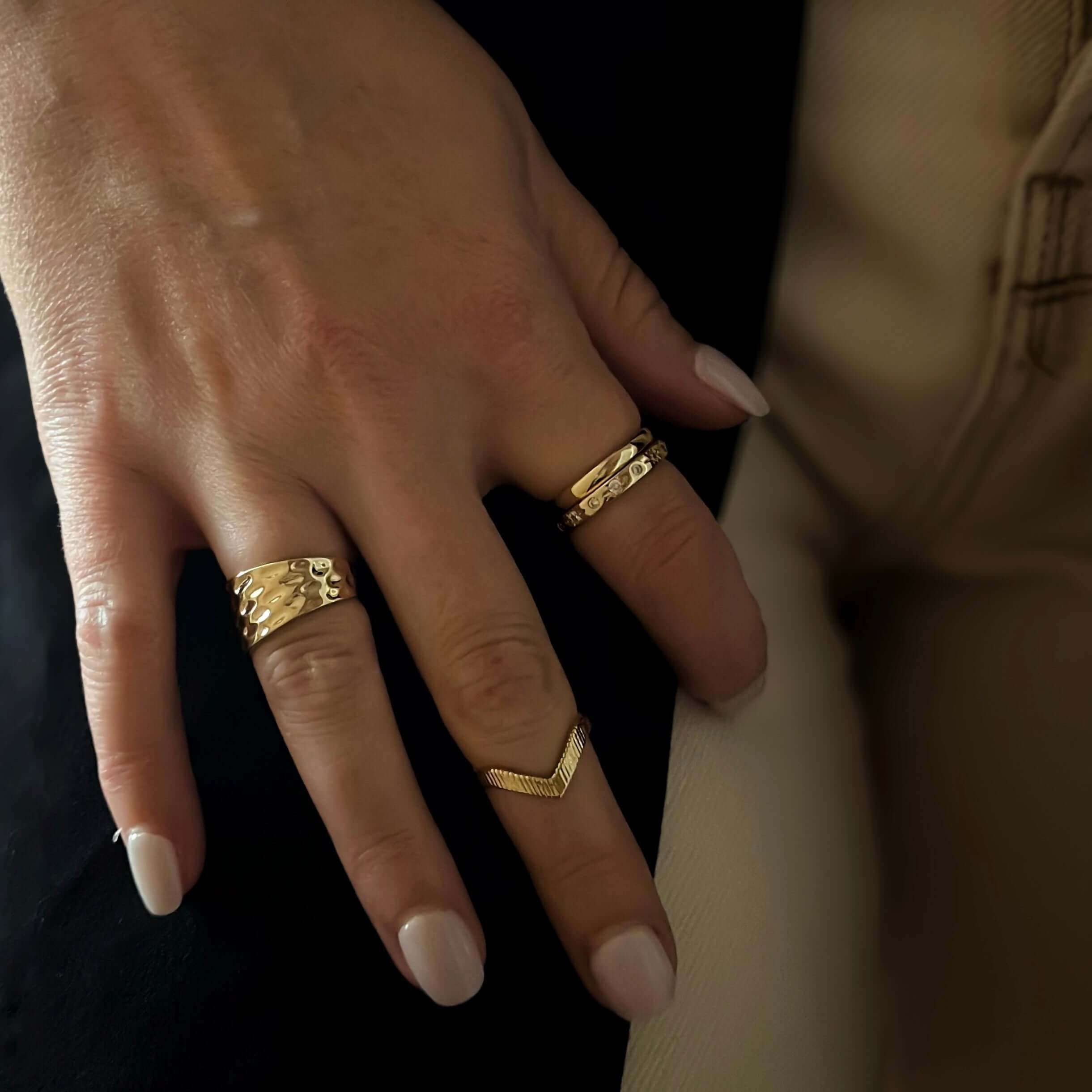 Close-up of a hand with manicured nails, showcasing three Summit Rings on the index, middle, and ring fingers, each exemplifying quality craftsmanship and unique design.
