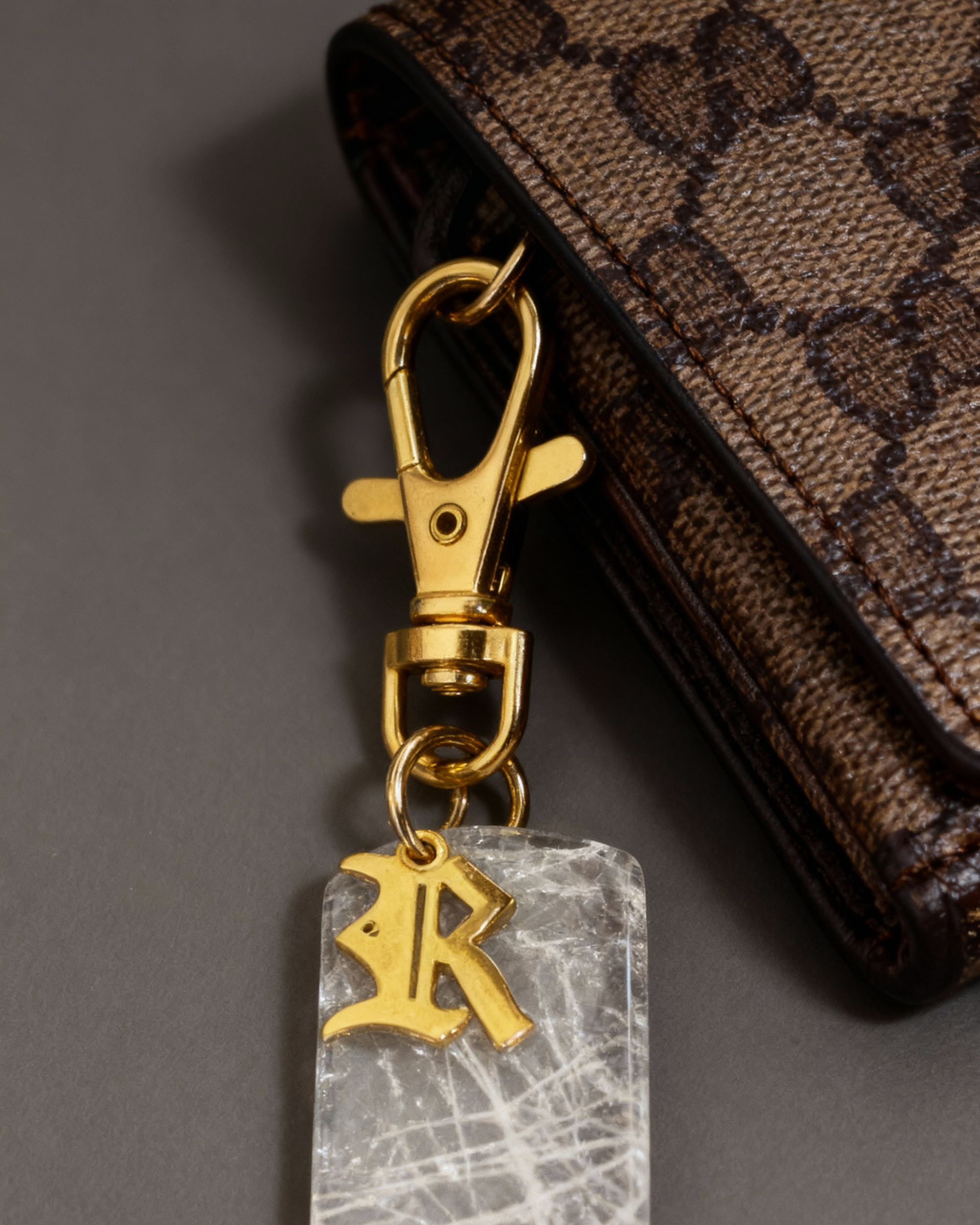 Gold-tone personalized crystal bag charm with lobster clasp and engraved locket pendant detail