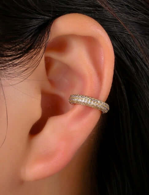 Close-up of an ear adorned with the Pave´ Wide Ear Cuff, a chic, sparkly gold accessory perfect for achieving a dazzling look without requiring any piercings.