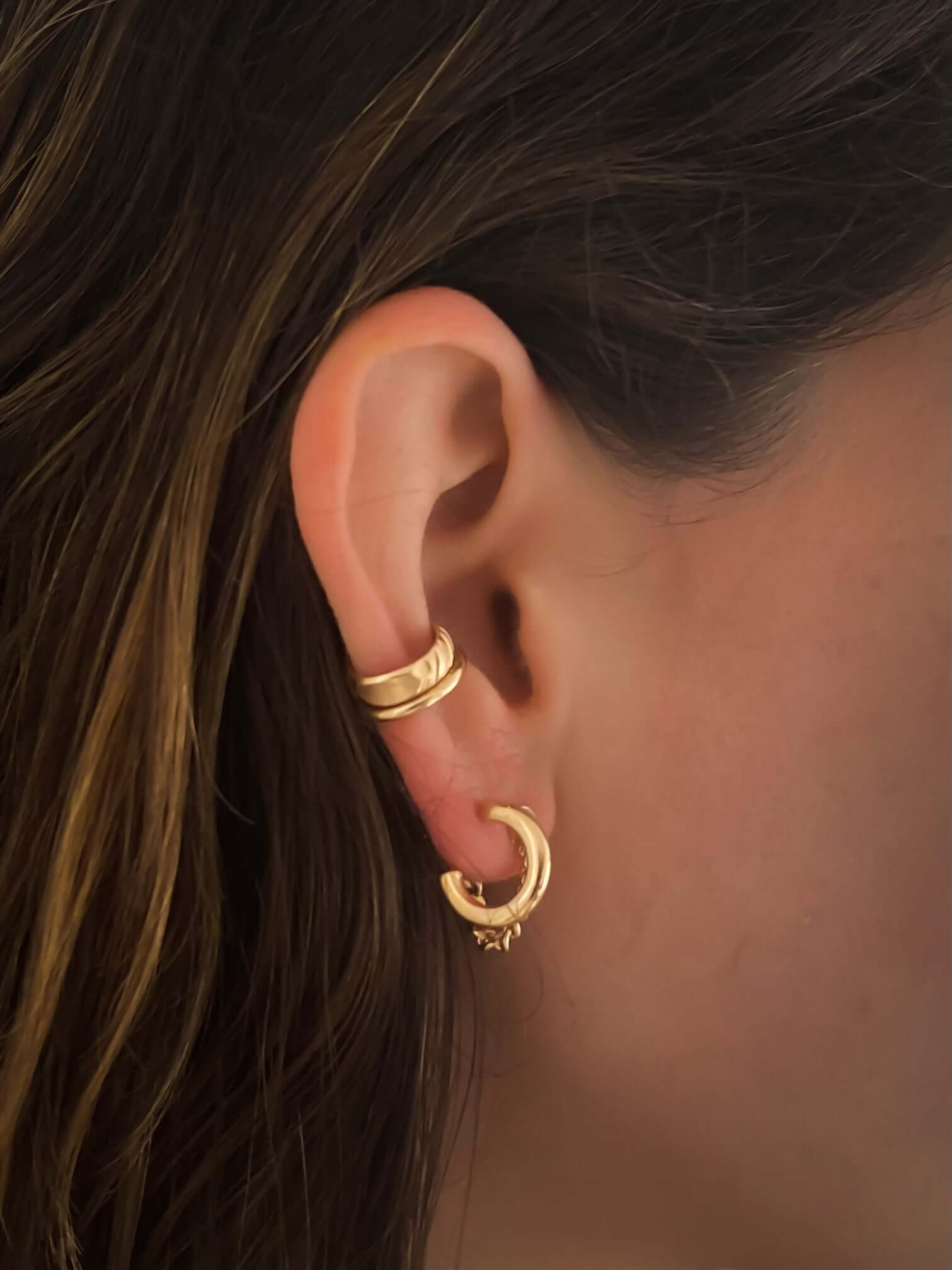 An ear adorned with the Edge Ear Cuff, a set of three elegant 14k gold-filled hoop earrings in varying sizes, worn on the lobe and cartilage.
