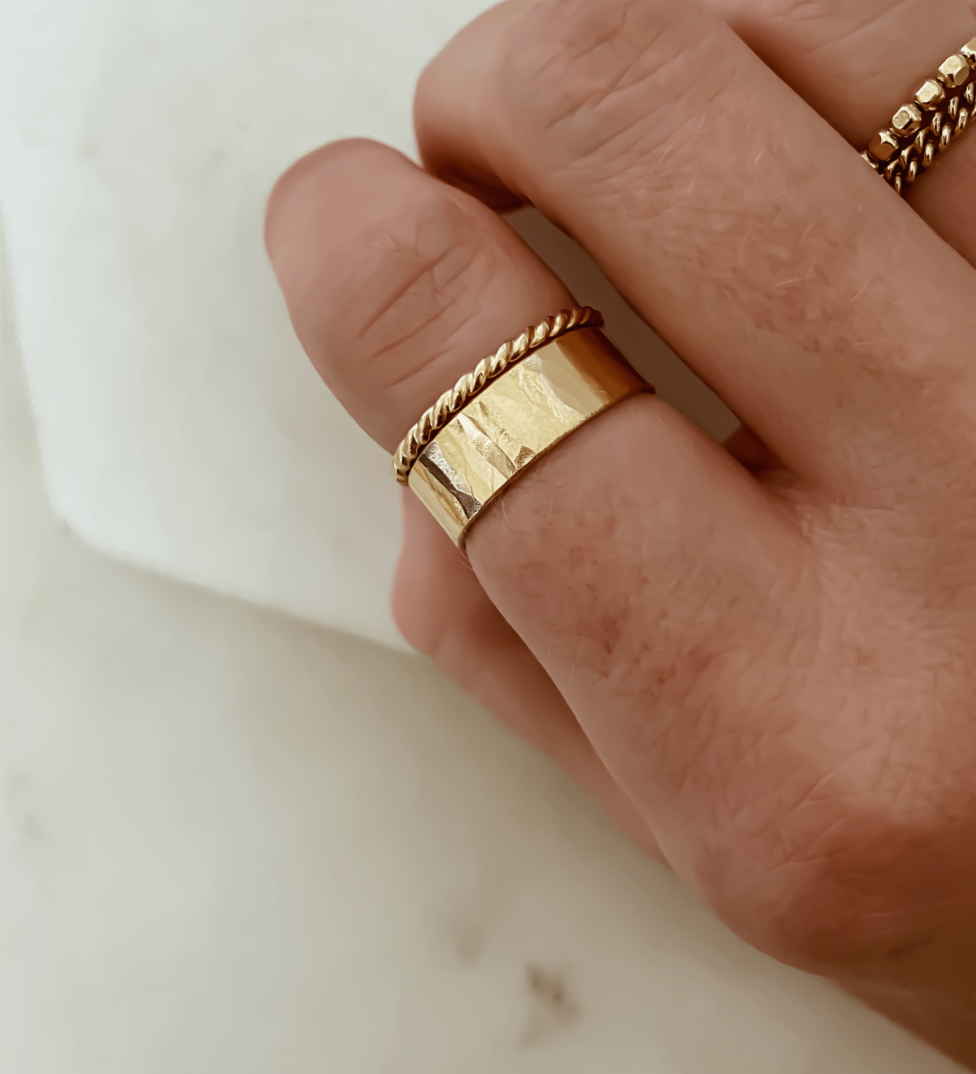 Close-up of a hand adorned with the Thin Twist Band alongside a plain gold band, ideal for stacking.