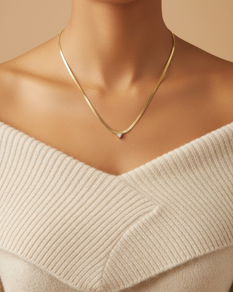 Close-up of a person wearing a gold necklace with a beige sweater.