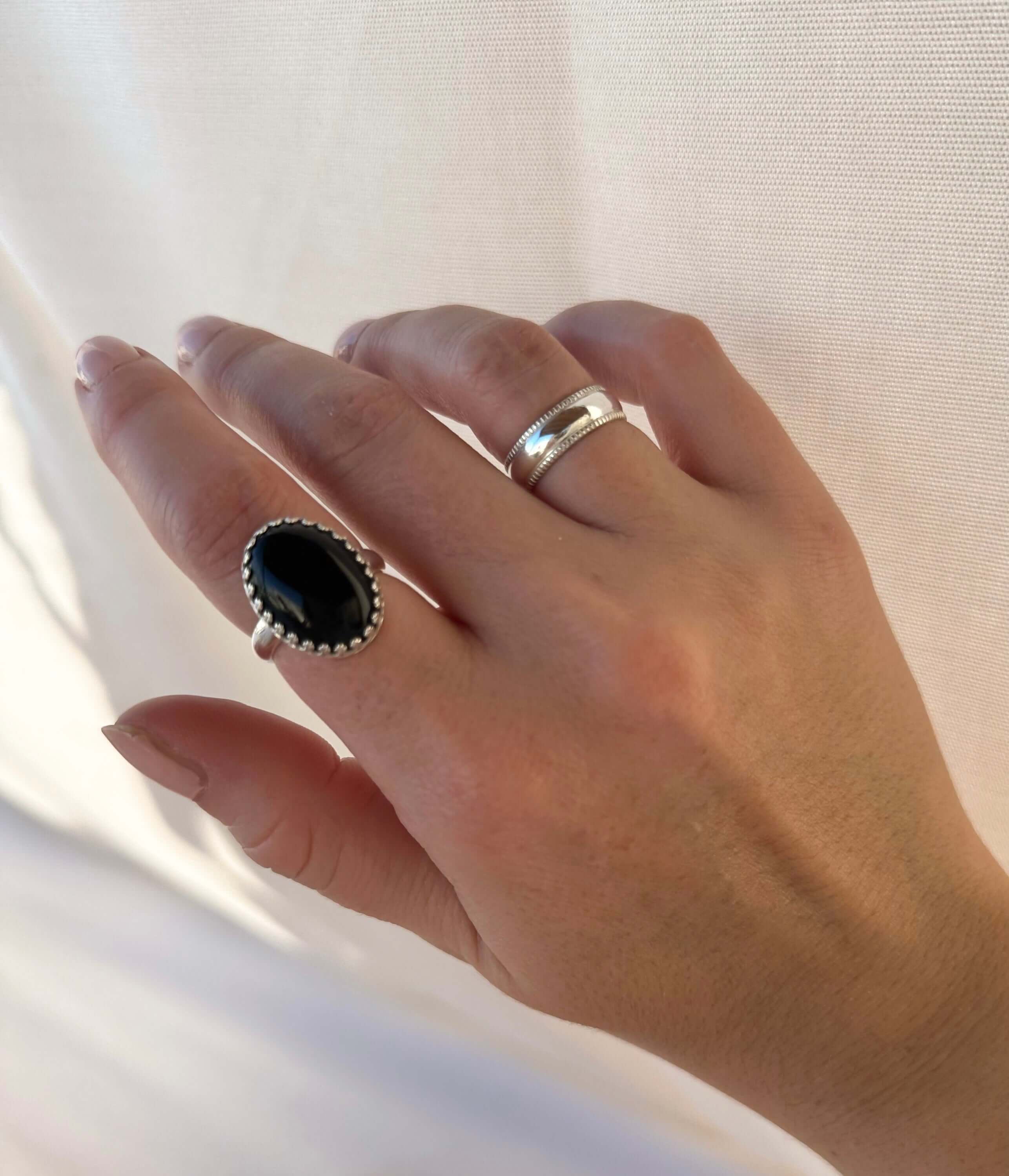 Hand adorned with a Selene Ring featuring a black stone set in sterling silver on the middle finger and a plain 14k gold-filled band on the ring finger.