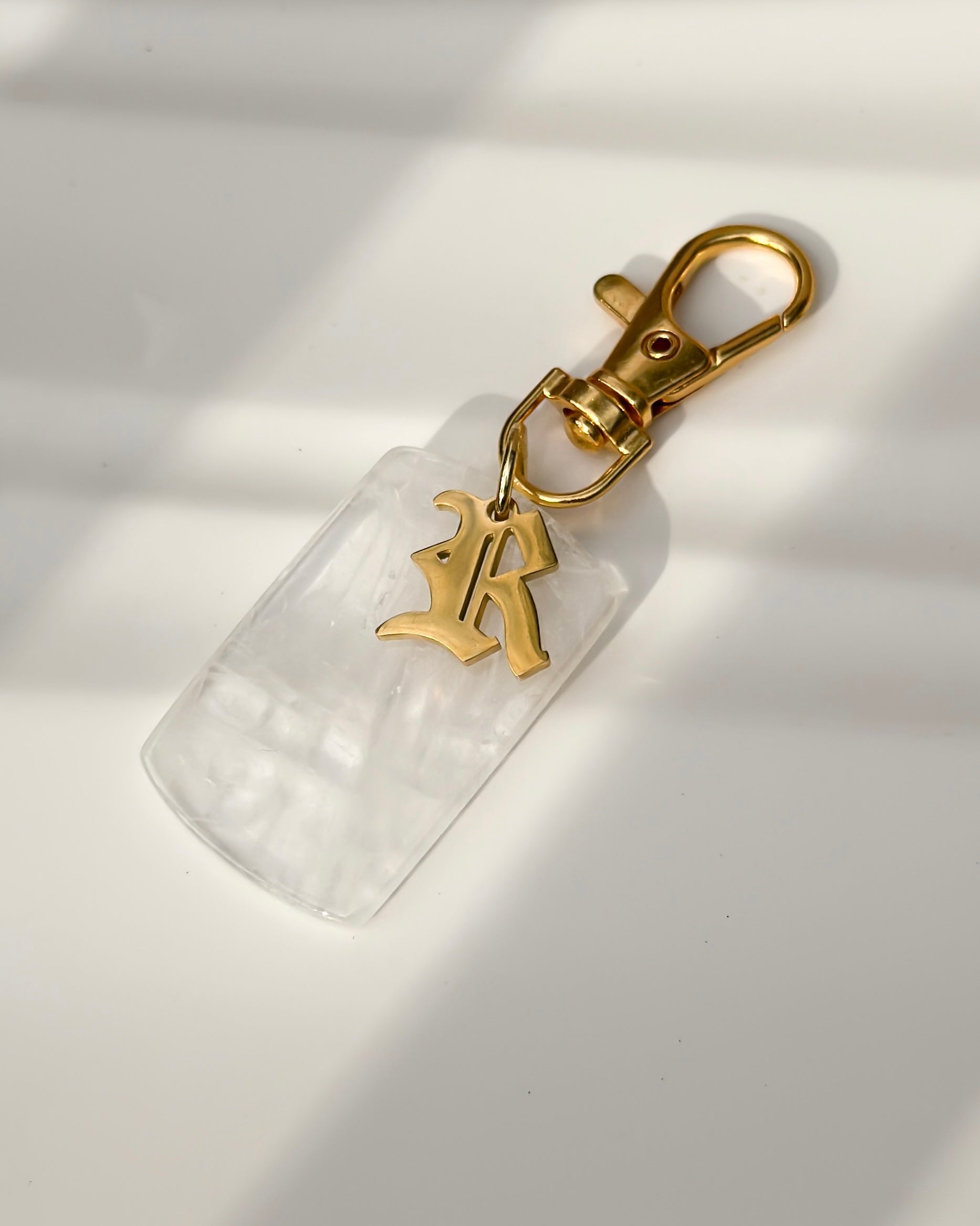 Gold-tone personalized crystal bag charm with lobster clasp and engraved locket pendant detail