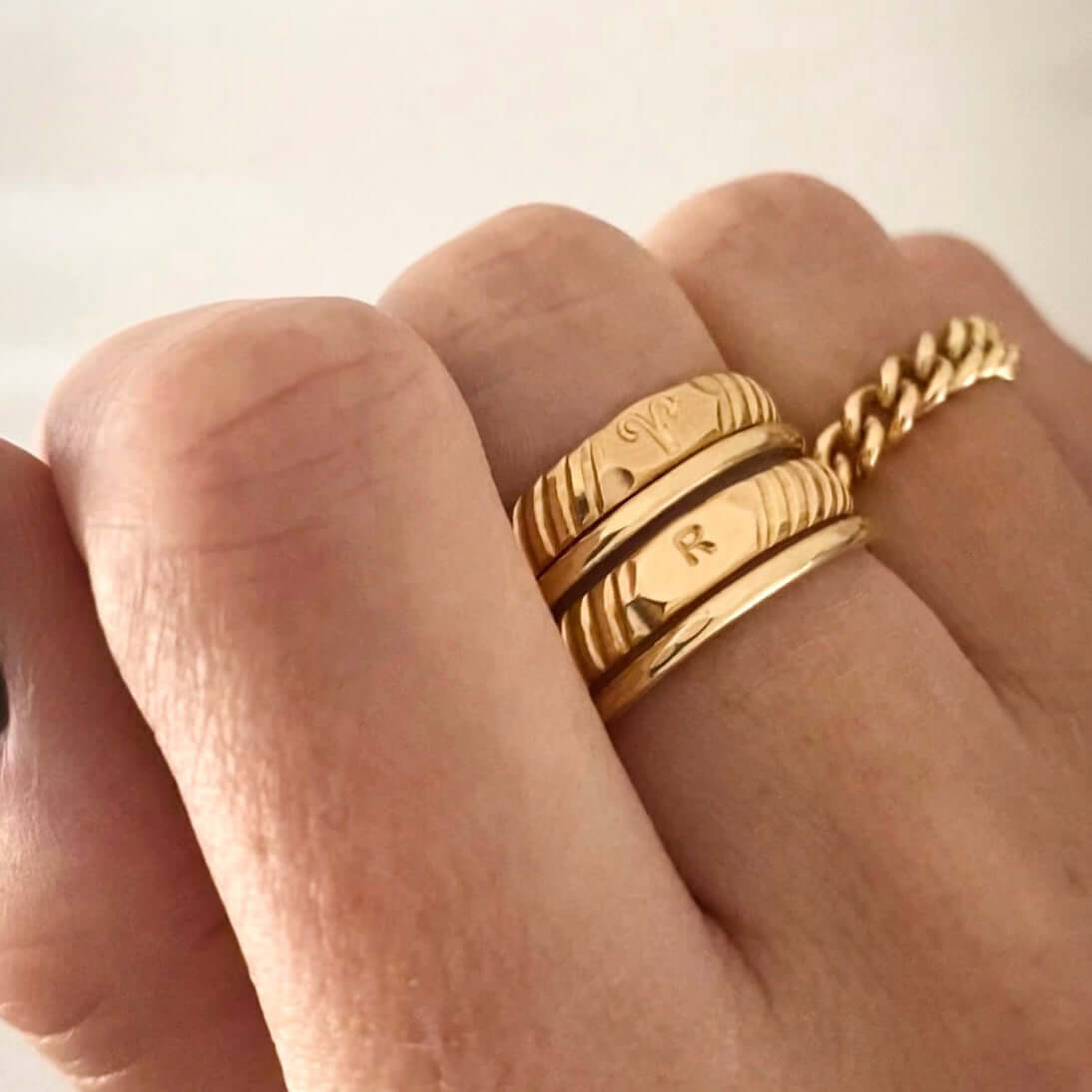 Close-up of a hand displaying two personalized Initial Signet Rings crafted in 14k gold filled material and a gold chain ring on the ring finger.